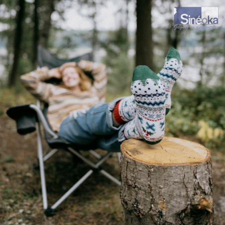 Chaussettes « Inga » en coton bio détente les 2 pieds sur une souche en forêt.